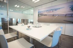 Een kleine vergaderzaal met een tafel, stoelen en een schilderij van Gorinchem